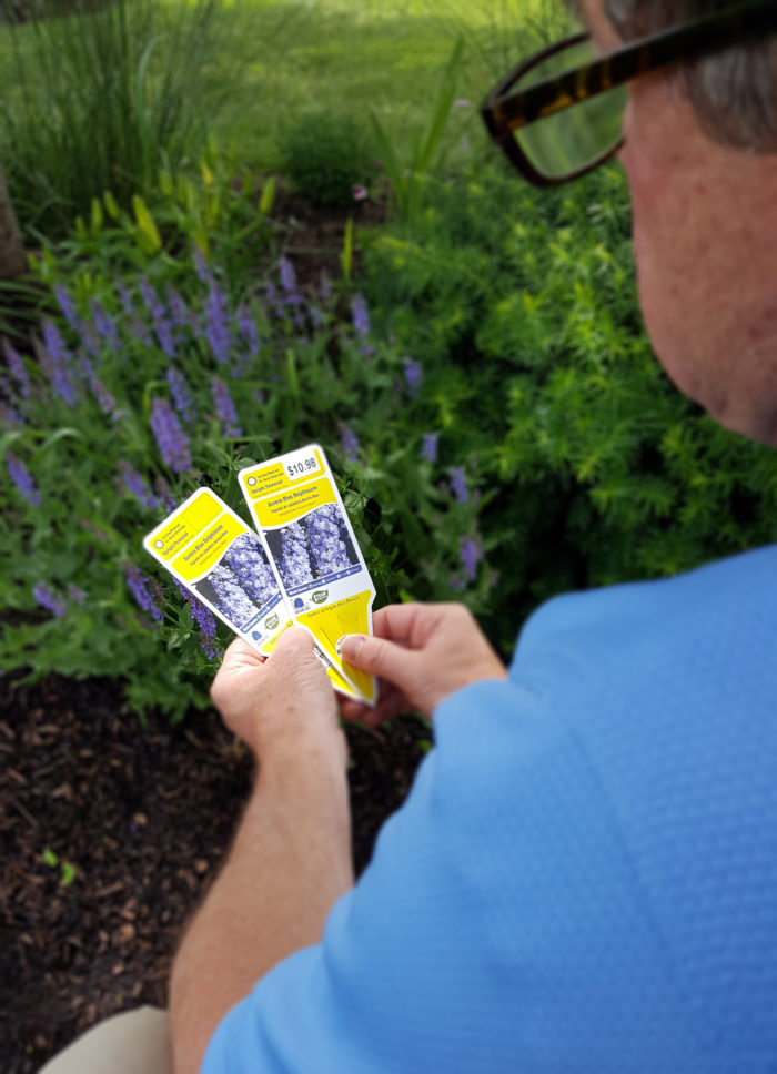 man holding plant tags - one is labeled