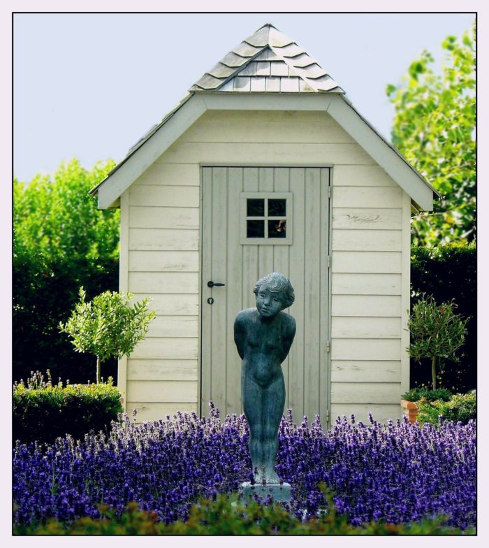 Garden shed with bright flowers and statue