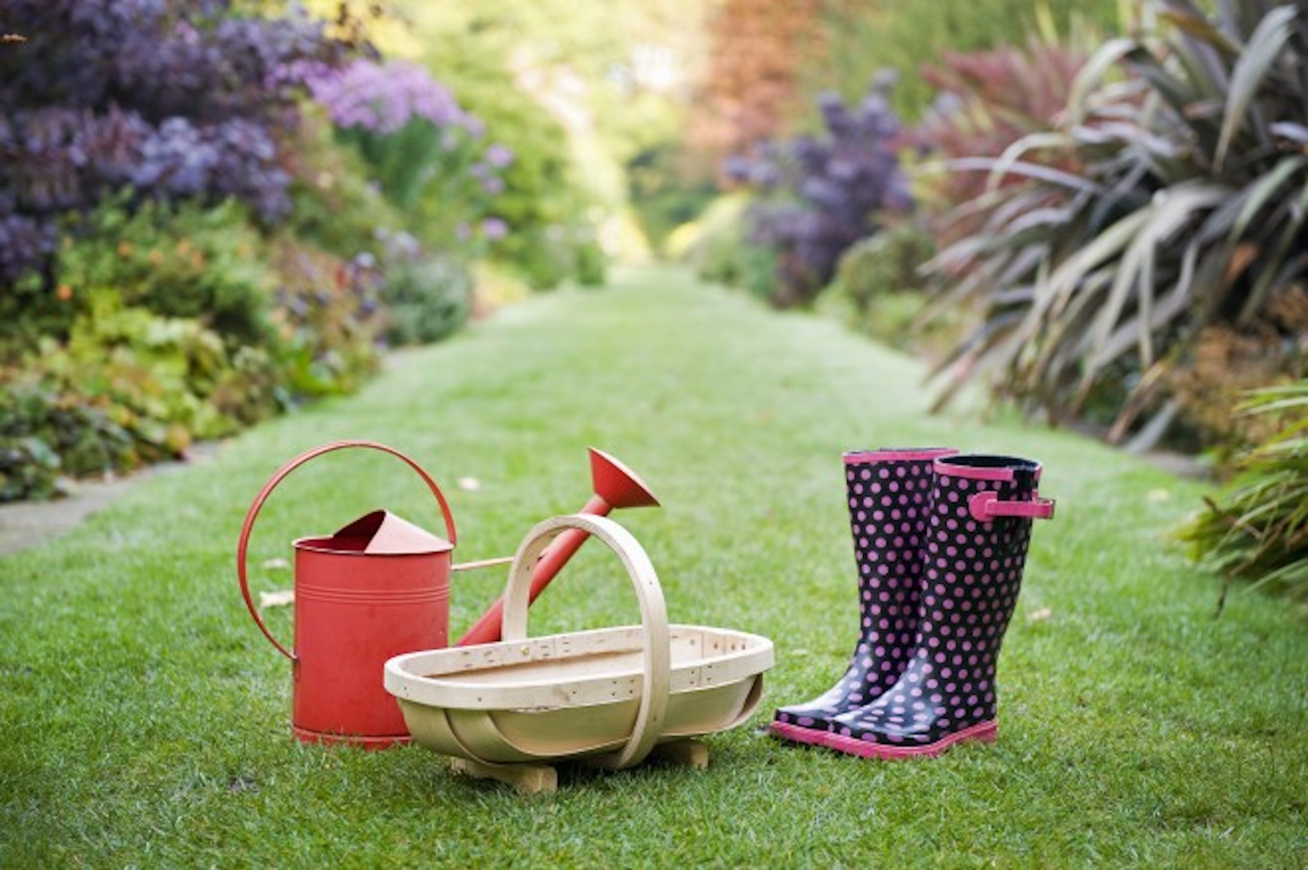 April Gardening Tips cover photo with boots and watering can in garden